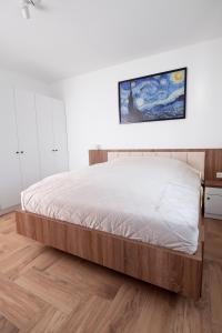 a bed in a bedroom with a wooden floor at HVT Comfort Apartments in Mezőkövesd