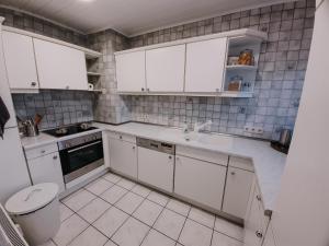 a white kitchen with white cabinets and a sink at Waldblick Herborn in Herborn