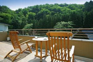 a patio with two chairs and a table on a balcony at 游泉志だて in Hanamaki