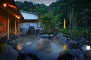 a pond with rocks in front of a house at 游泉志だて in Hanamaki