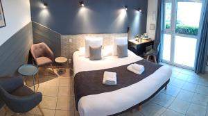 a hotel room with a large bed and two chairs at Logis Hôtel La Rosière----Situé entre BAYEUX et ARROMANCHES in Tracy-sur-Mer