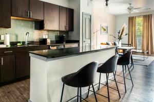 a kitchen with a bar with stools around it at Placemakr Music Row in Nashville