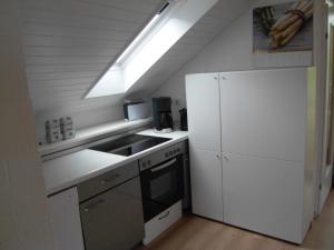 a white kitchen with a sink and a refrigerator at Ferienwohnungen Gabi Karnowski in Gernsbach