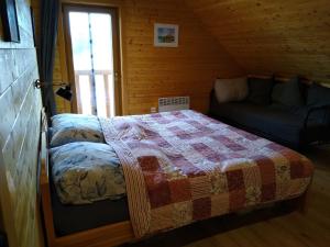1 dormitorio con 1 cama y 1 sofá en una cabaña en Zrub Kukučka, en Liptovský Trnovec