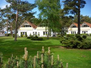 プレローにあるFerienanlage "Haus hinter den Dünen" Prerowの木々と緑の芝生の白い家