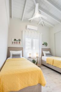Duas camas num quarto branco com lençóis amarelos em Marika's Penthouse Chania em Chania Town