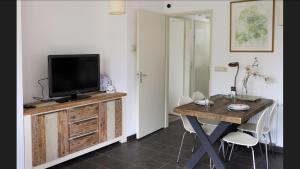 a living room with a tv and a table with chairs at Huinerhofje 2 - Vrijstaand met grote omheinde tuin, rust, privacy en nabij bossen in Putten