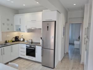 uma cozinha com armários brancos e um frigorífico de aço inoxidável em Marika's Penthouse Chania em Chania Town