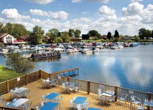 a deck with tables and chairs next to a marina at Billing Aquadrome in Great Billing