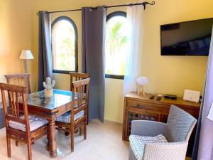 a dining room with a table and chairs and two windows at Cosy apartment in Corralejo, shared pool, 55 m² in Corralejo