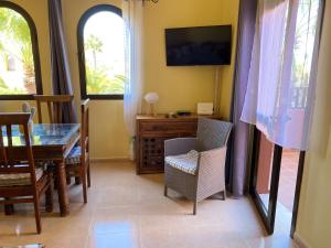 a dining room with a table and chairs and a television at Cosy apartment in Corralejo, shared pool, 55 m² in Corralejo