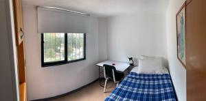 a bedroom with a bed and a desk and a window at Hostel U in Bogotá