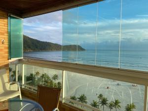 a room with a view of the beach and the ocean at Apto Varanda Gourmet frente ao mar com Wi-Fi in Praia Grande