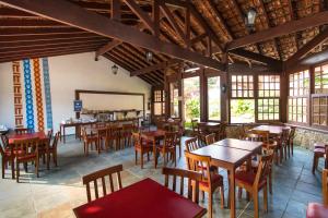 a restaurant with wooden tables and chairs and windows at HOTELARE Hotel Villa Di Capri in Ubatuba