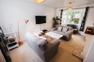 ein Wohnzimmer mit 2 Sofas und einem TV in der Unterkunft Booker Avenue House - 4 bedroom house with garden and parking in Milton Keynes