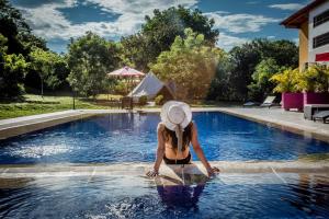 eine Frau mit Hut sitzt in einem Swimmingpool in der Unterkunft Mangoo Glamping in Melgar