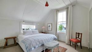 a white bedroom with a bed and a chair at Timeless 2BR Grey Lynn Cottage - Fibre - WiFi in Auckland