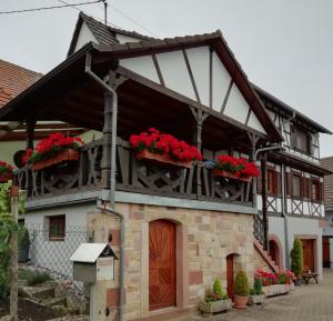 a house with red flowers on the balcony at Gîte HAURY in Cleebourg