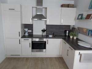 uma cozinha com armários brancos e um forno de aço inoxidável em App-Waterkant-STR-10A em Scharbeutz
