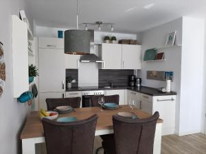 uma cozinha com uma mesa de madeira e cadeiras numa cozinha em App-Waterkant-STR-10A em Scharbeutz