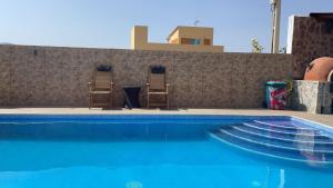 una piscina con 2 sillas junto a una pared en Habitación en Casa Denube en Las Playitas