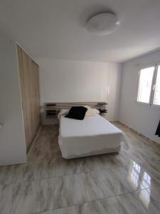 a white bedroom with a bed and a mirror at Habitación en Casa Denube in Las Playitas