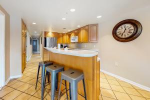 a kitchen with a bar with stools and a clock on the wall at Sea Palms in Ocean City