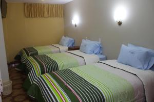 ein Hotelzimmer mit 3 Betten und blauen Kissen in der Unterkunft Hotel Alpamayo Cajamarca in Cajamarca