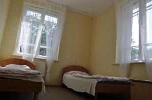 two beds in a room with two windows at OW Tęcza Przy Plaży in Krynica Morska