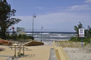 einen Strand mit Bänken und das Meer im Hintergrund in der Unterkunft OW Tęcza Przy Plaży in Krynica Morska