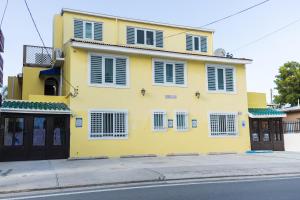 a yellow house with white shutters on a street at Andalucia Guest House in San Juan