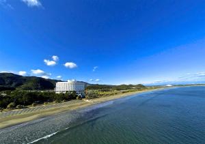 ANA Holiday Inn Resort Miyazaki, an IHG Hotel في ميازاكي: اطلاله على شاطئ مع مبنى والمحيط