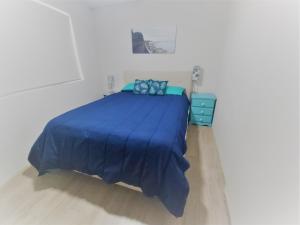 a bed in a white room with a blue blanket at Moondara Unit 2 21 Bulcock Beach Esplanade Bulcock Beach in Caloundra