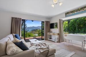 een woonkamer met een bank en een groot raam bij Woodside - Akaroa Holiday Cottage in Akaroa