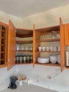 a kitchen with wooden cabinets with plates and bowls at HOUSE IN FRONT OF THE BEACH WITH POOL. COMFORTABLE in San Luis