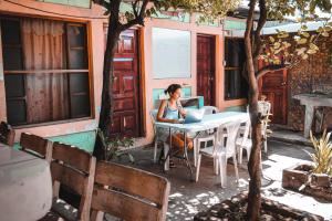 una mujer sentada en una mesa con un portátil en Hostal Los Chamos, en San Juan del Sur