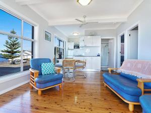a living room with a blue couch and chairs and a kitchen at Beachcomer 1 in The Entrance