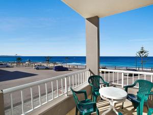 uma varanda com mesa e cadeiras e a praia em Beachcomer 1 em The Entrance