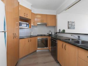 a kitchen with wooden cabinets and stainless steel appliances at Crystal Waters Unit 11 in The Entrance