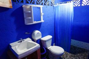 a blue bathroom with a toilet and a sink at Hostal Los Chamos in San Juan del Sur