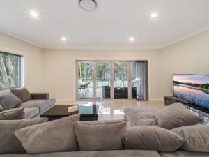uma sala de estar com um sofá grande e uma televisão de ecrã plano em Lakedge Home em Berkeley Vale