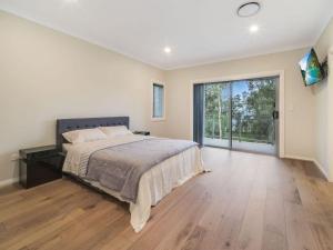 um quarto com uma cama grande e uma janela grande em Lakedge Home em Berkeley Vale