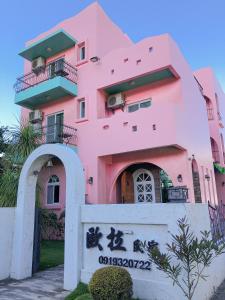 een roze gebouw met een bord ervoor bij 歐拉民宿 l 大空間包棟 l 親子溜滑梯 l 專業音響 in Taitung