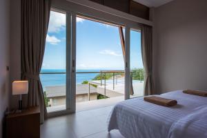 ein Schlafzimmer mit großem Fenster mit Blick auf das Meer in der Unterkunft Bay Villas Koh Phangan in Salad Beach