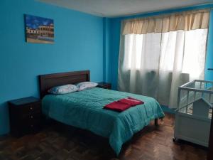 a blue bedroom with a bed with a green blanket at Amplio y cómodo departamento. in Loja