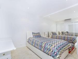 a white bedroom with two beds and a mirror at Perfect Beach Front Duplex - The Entrance North in The Entrance