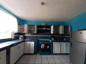 uma cozinha com paredes azuis, armários brancos e um frigorífico em Amplio y cómodo departamento. em Loja