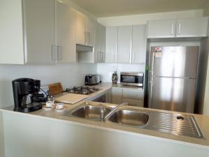 a kitchen with a sink and a stainless steel refrigerator at Ocean Views Sundrift Unit 26 in The Entrance