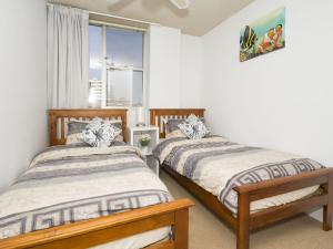two beds in a room with a window at Tasman Towers Unit 13 in The Entrance