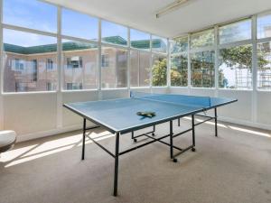 una mesa de ping pong en una habitación con ventanas en The Sands Unit 5, en The Entrance